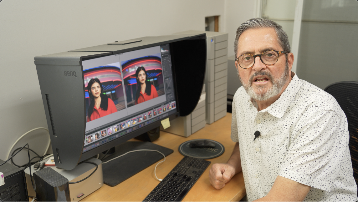 Man editing photos on a dual-screen computer setup with color calibration hood.
